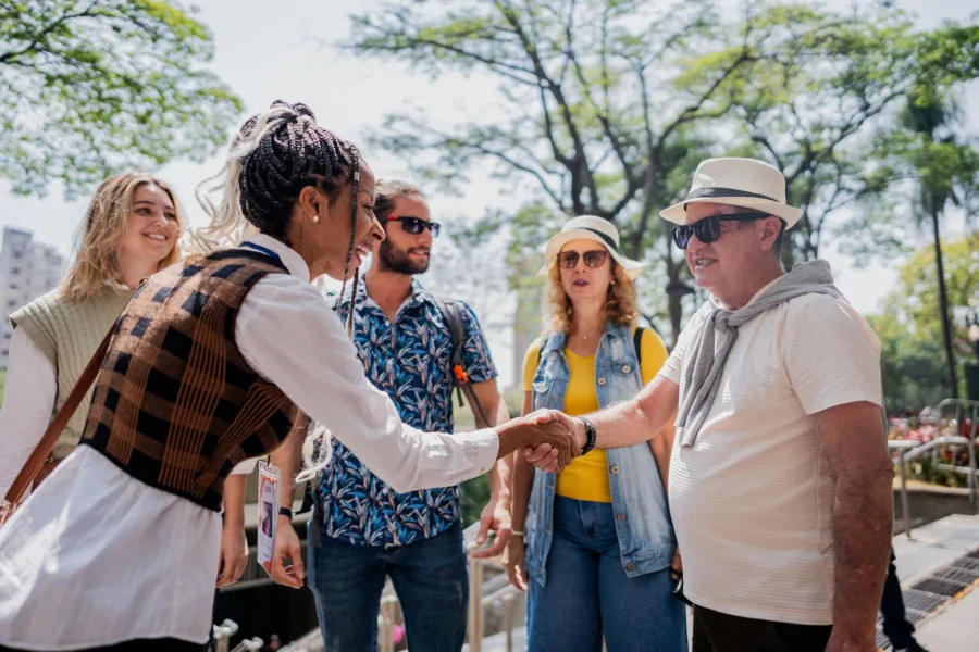 Karla saluda a un viajero en un parque arbolado durante una experiencia de turismo guiado.
